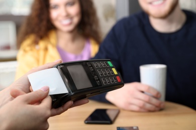 Clients using credit card machine for non cash payment in cafe, closeup