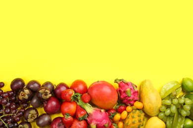 Assortment of fresh exotic fruits on yellow background, flat lay. Space for text