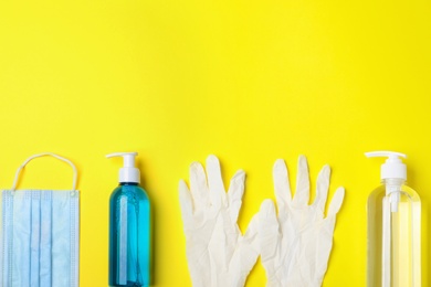 Photo of Medical gloves, mask and hand sanitizers on yellow background, flat lay. Space for text
