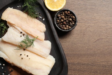 Raw cod fish, dill and spices on wooden table, top view. Space for text