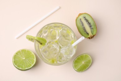 Photo of Glass of refreshing drink, cut kiwi and lime on beige background, flat lay
