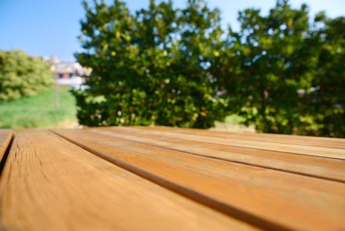 Photo of Empty wooden picnic table in park on sunny day, closeup