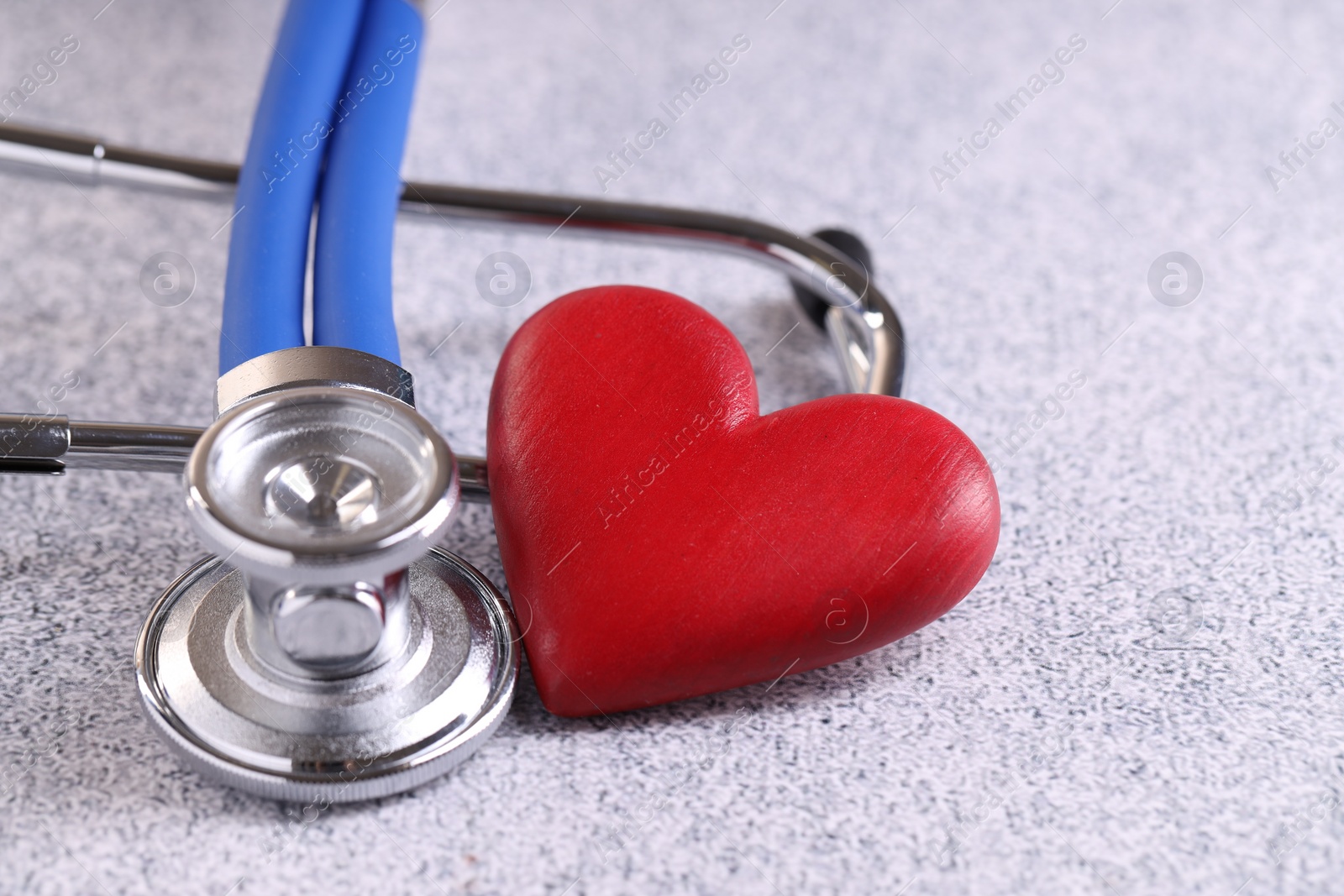 Photo of Stethoscope and red heart on grey stone table