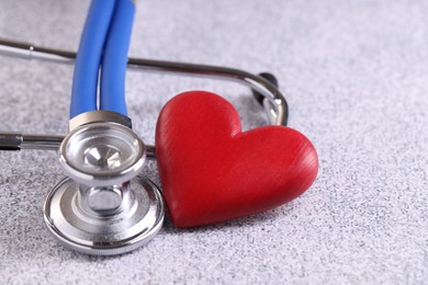 Stethoscope and red heart on grey stone table