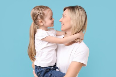 Family portrait of happy mother and daughter on light blue background