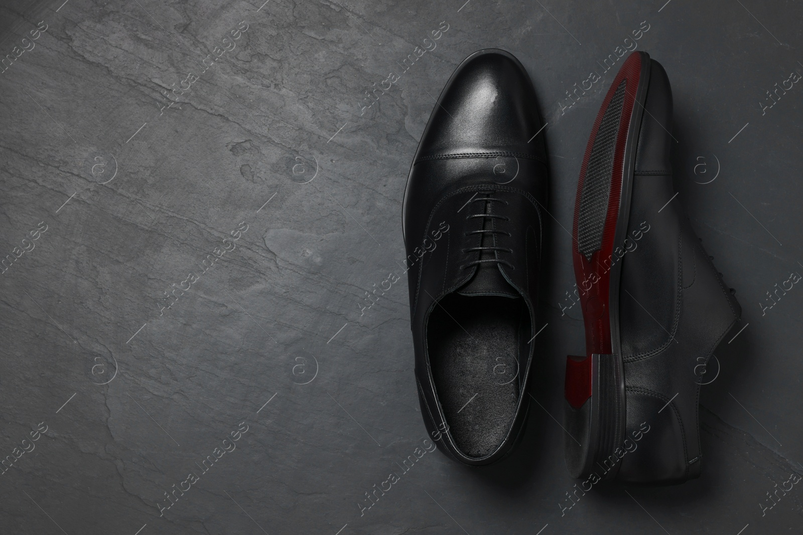 Photo of Pair of leather men shoes on black surface, top view. Space for text