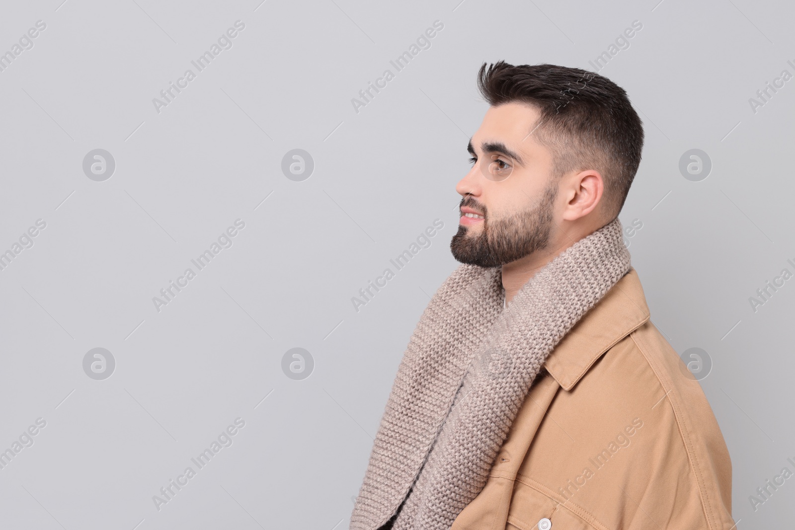 Photo of Handsome man in warm scarf on light grey background. Space for text