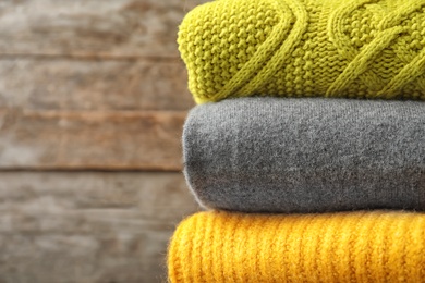 Photo of Stack of warm knitted clothes on blurred background