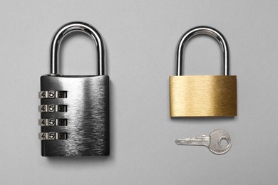 Photo of Different padlocks and key on grey background, top view