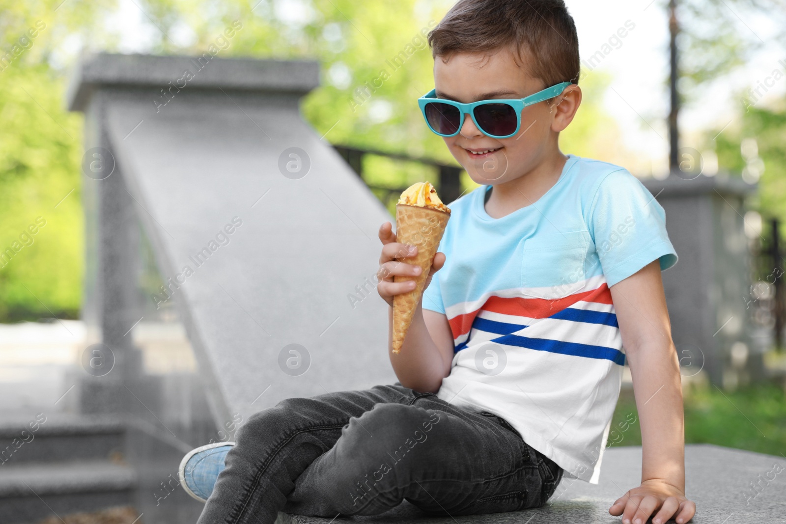 Photo of Cute little boy with delicious ice cream outdoors, space for text