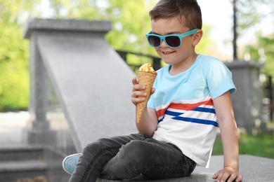 Cute little boy with delicious ice cream outdoors, space for text