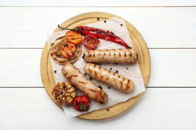 Photo of Tasty grilled sausages with vegetables on white wooden table, top view