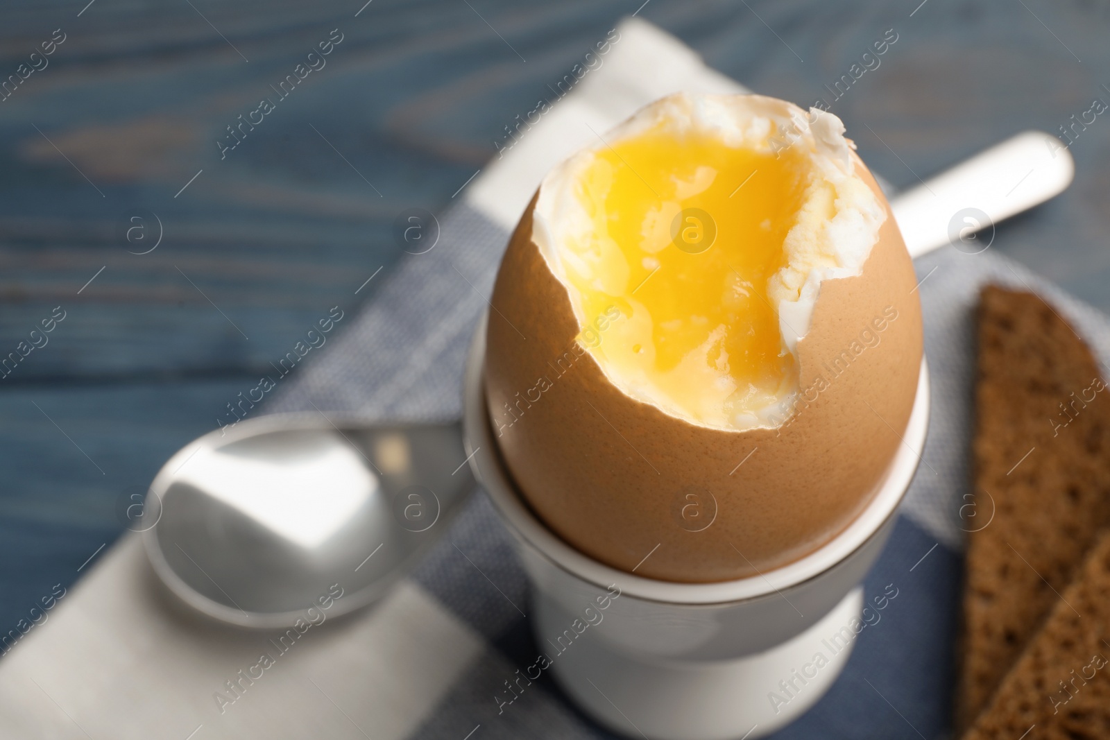 Photo of Holder with soft boiled egg on table, closeup. Space for text