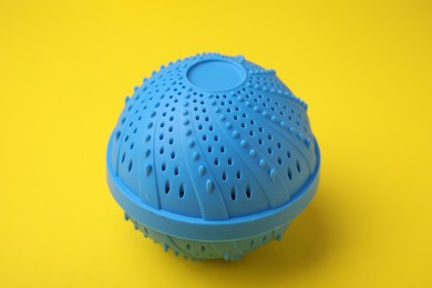 Photo of Dryer ball for washing machine on yellow background. Laundry detergent substitute