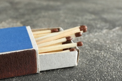 Photo of Open box with matches on grey background, space for text