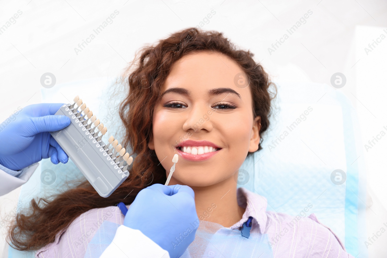 Photo of Dentist matching patient's teeth color with palette in office