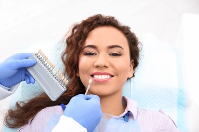 Dentist matching patient's teeth color with palette in office