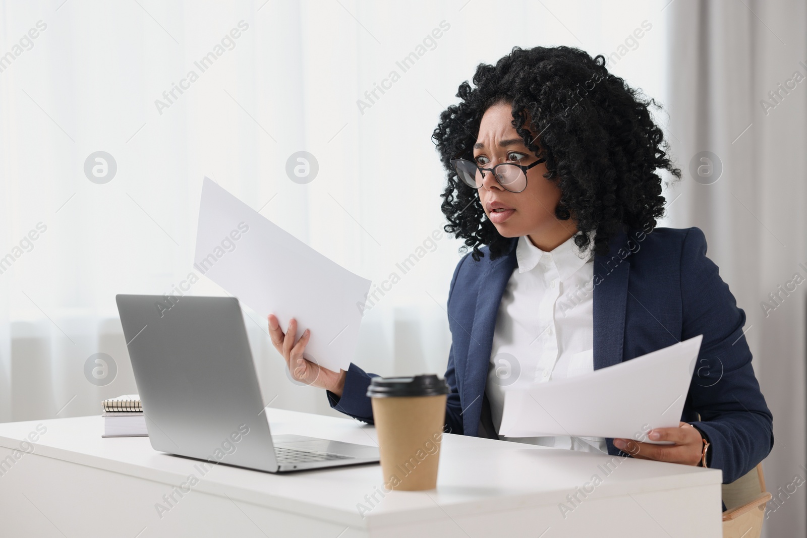 Photo of Deadline concept. Scared woman holding documents and looking at laptop in office