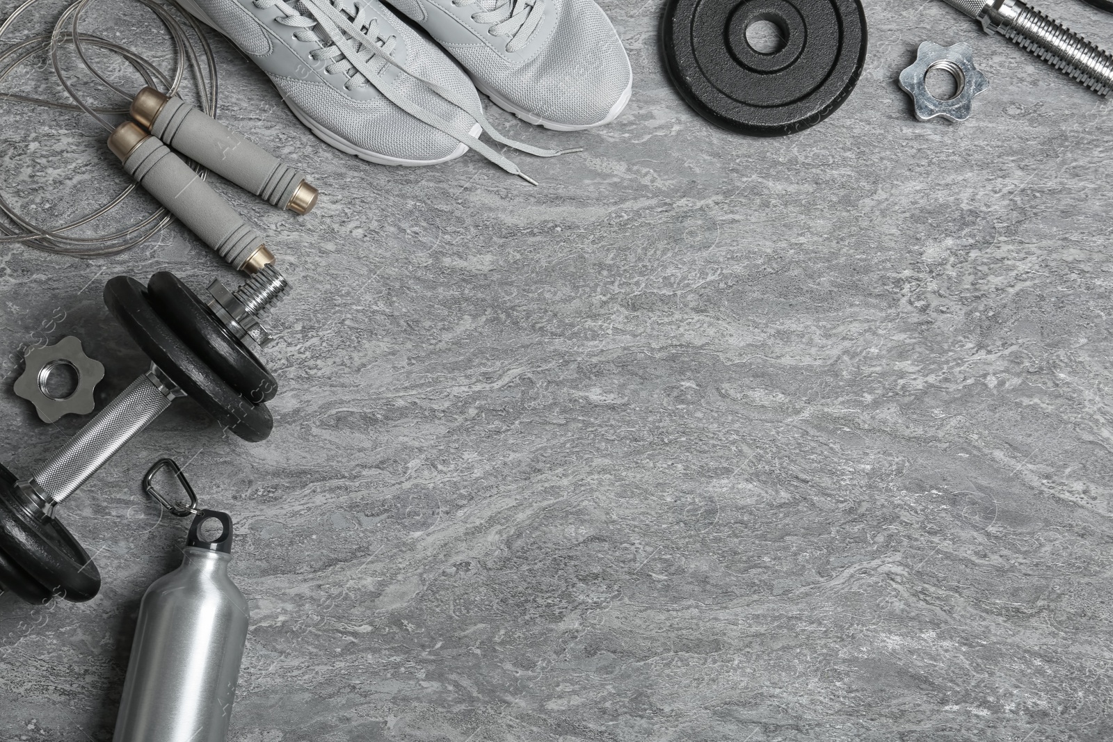 Photo of Flat lay composition with dumbbell and fitness accessories on grey background. Space for text