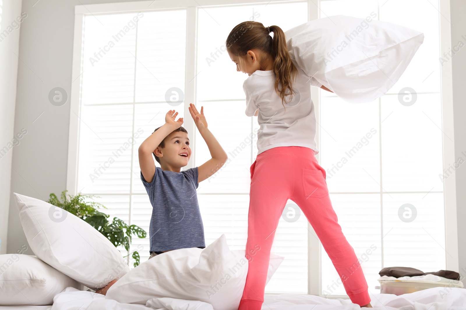 Photo of Happy children having pillow fight in bedroom