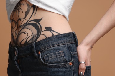Photo of Woman with cool tattoos on beige background, closeup