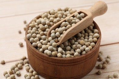 Aromatic spice. White peppers and scoop in bowl on wooden table, closeup