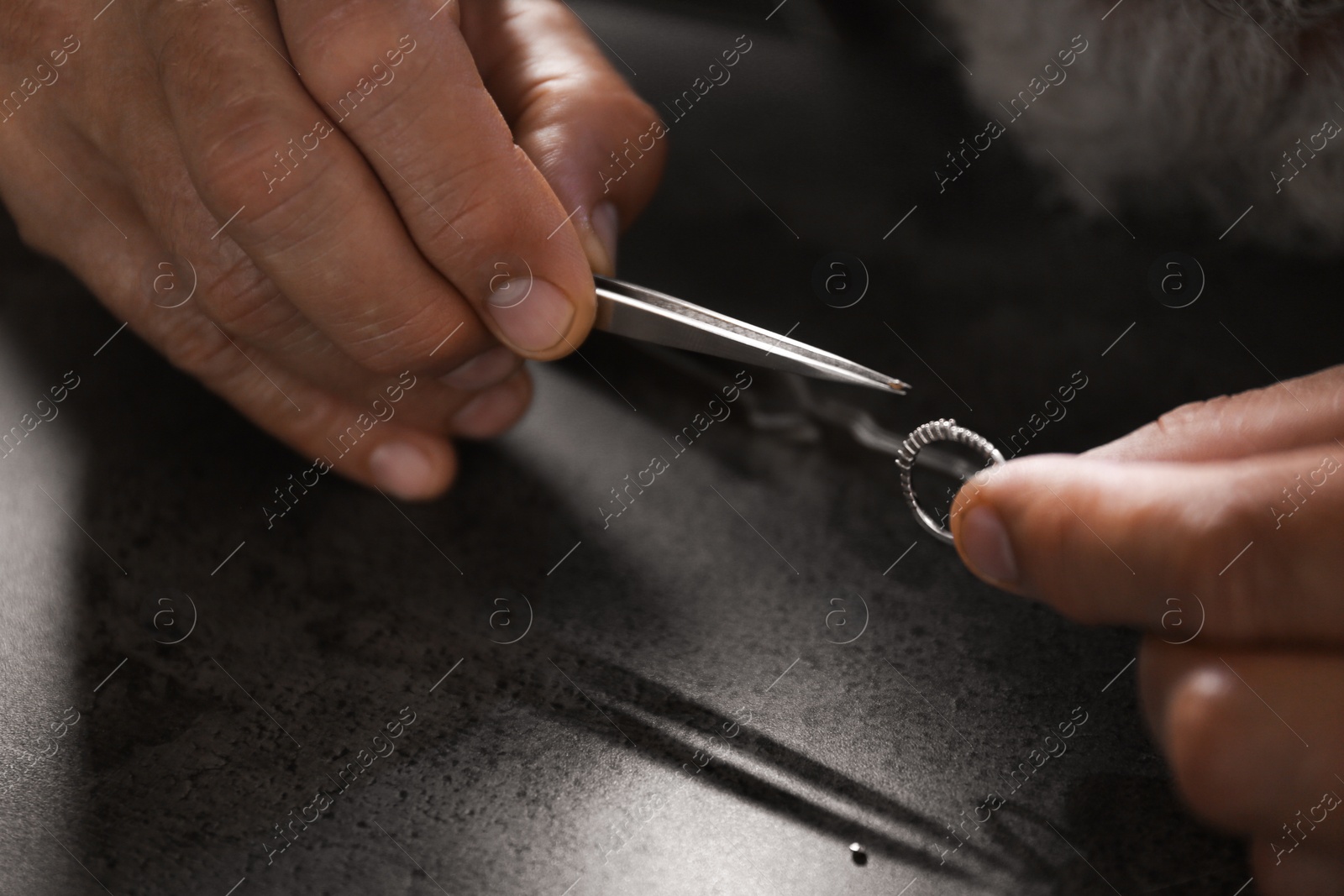 Photo of Male jeweler examining diamond ring in workshop, closeup view