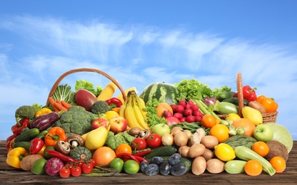 Image of Assortment of fresh organic fruits and vegetables on wooden table outdoors 