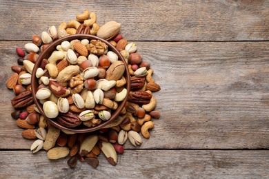 Photo of Flat lay composition with mixed organic nuts and space for text on wooden background, top view