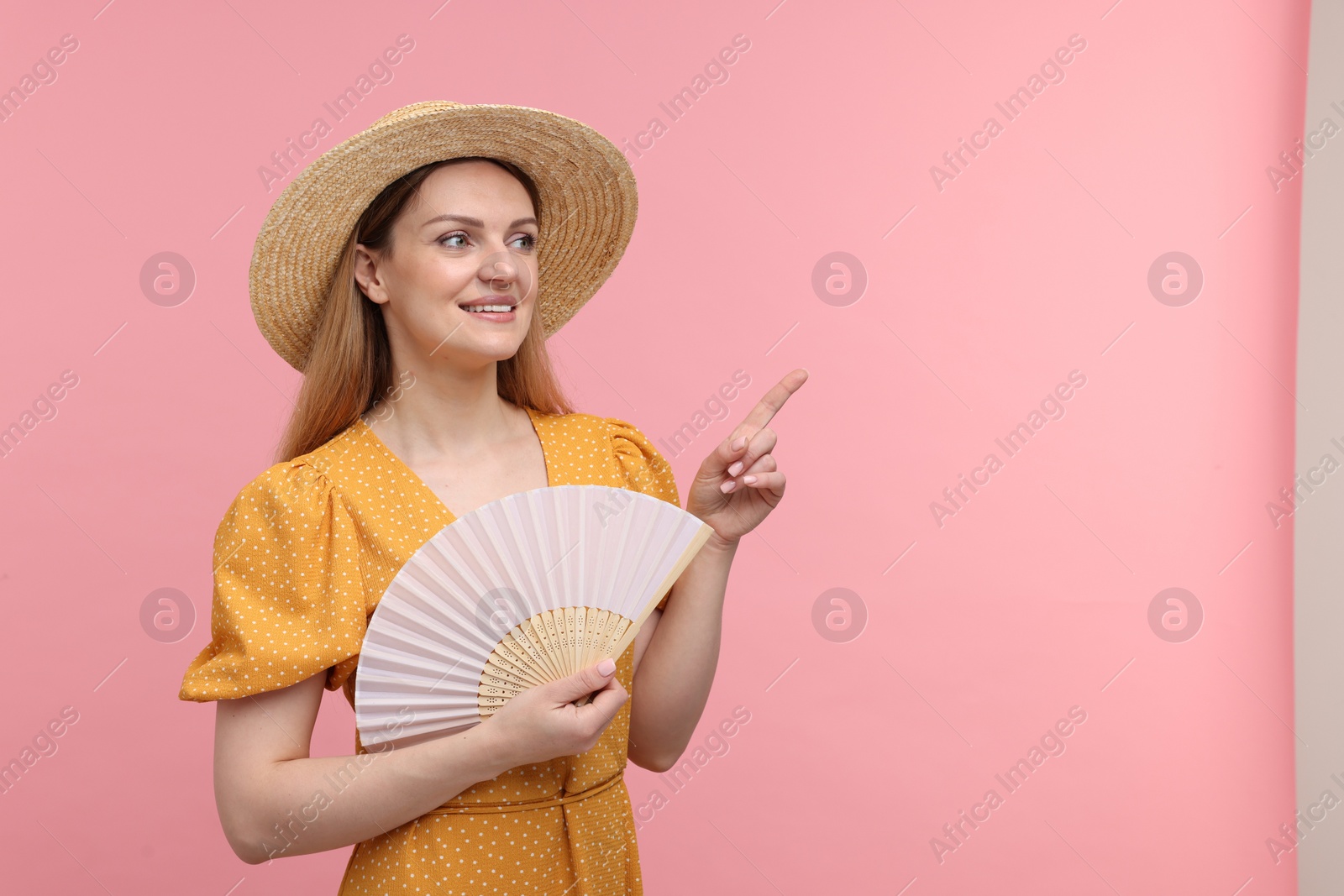 Photo of Happy woman with hand fan pointing on pink background