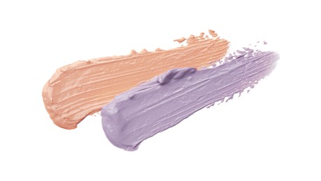 Photo of Strokes of pink and purple color correcting concealers isolated on white