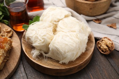 Photo of Eastern sweets. Tasty Iranian pashmak and tea on wooden table, closeup