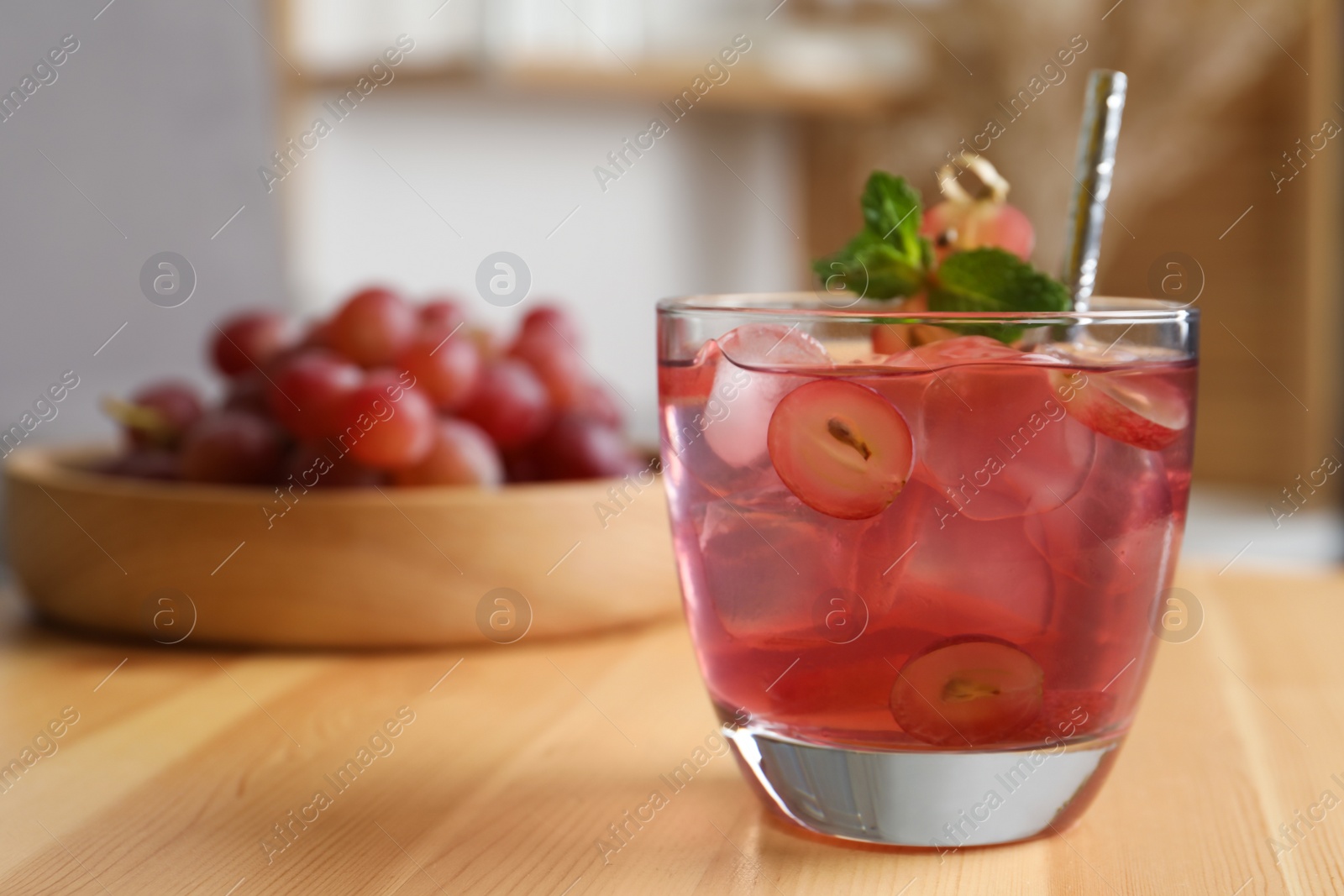 Photo of Refreshing drink with soda water, grapes, ice and mint on wooden table indoors. Space for text