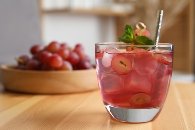 Photo of Refreshing drink with soda water, grapes, ice and mint on wooden table indoors. Space for text