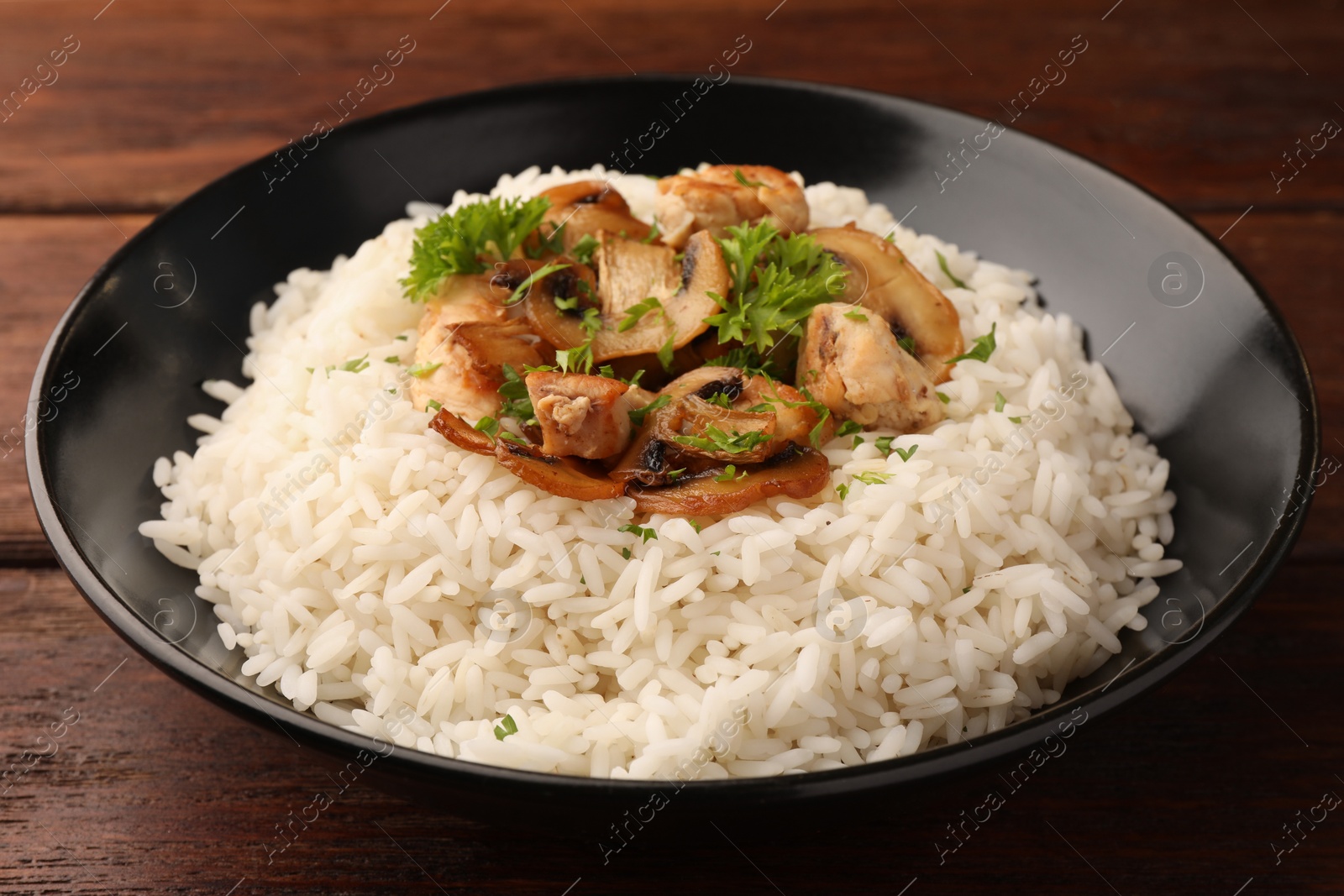 Photo of Delicious rice with mushrooms and parsley on wooden table, closeup