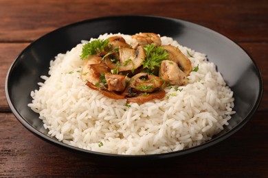 Delicious rice with mushrooms and parsley on wooden table, closeup