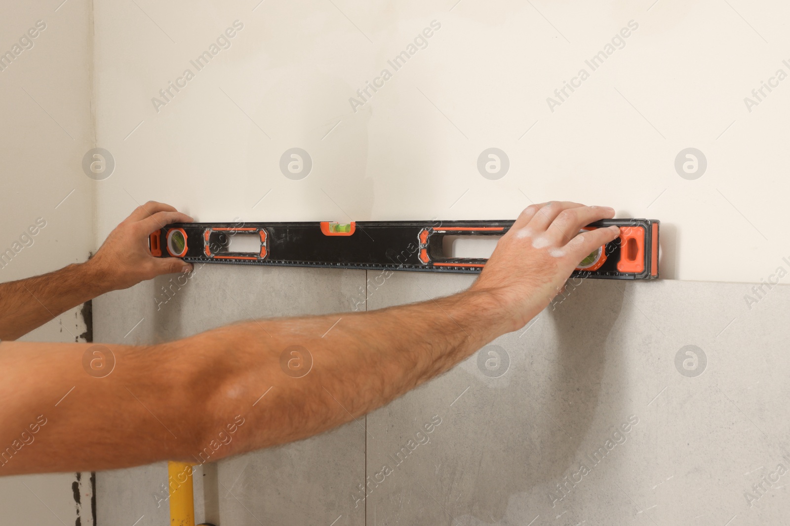 Photo of Worker installing tiles indoors, closeup. Home improvement