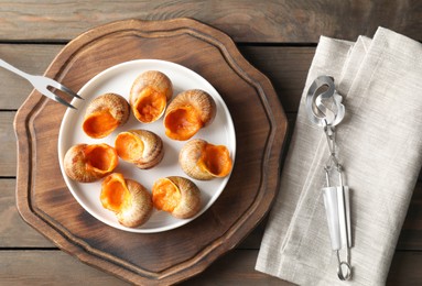 Delicious cooked snails served on wooden table, flat lay