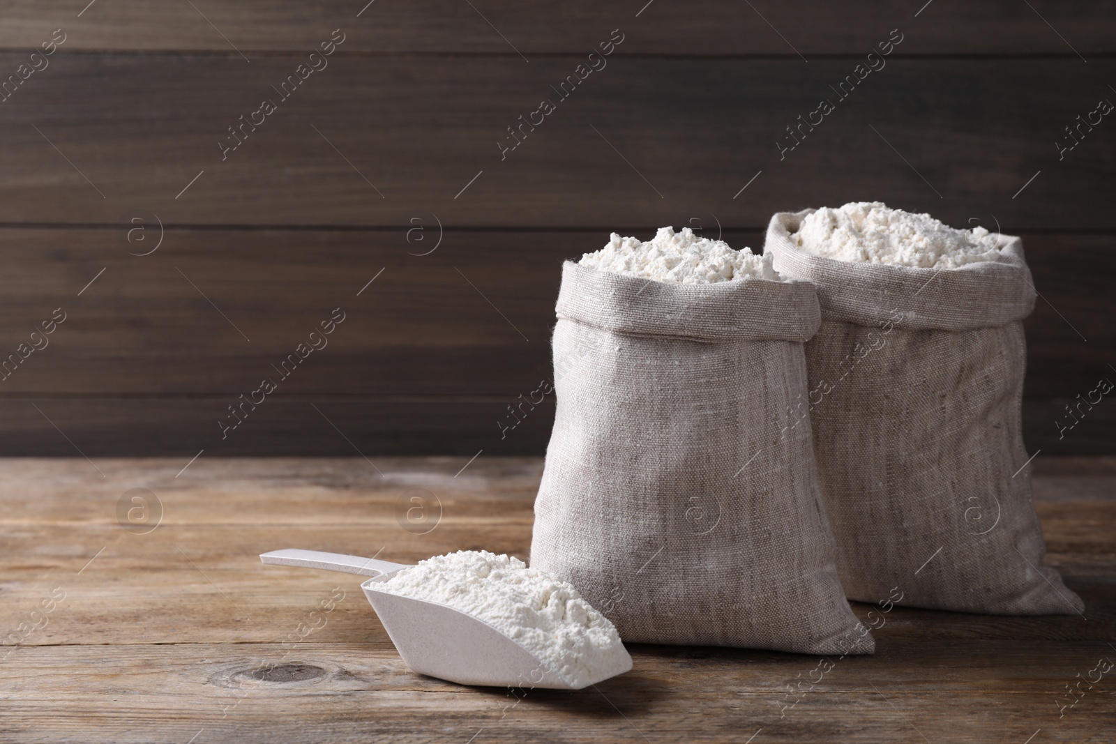 Photo of Sacks with flour on wooden background. Space for text