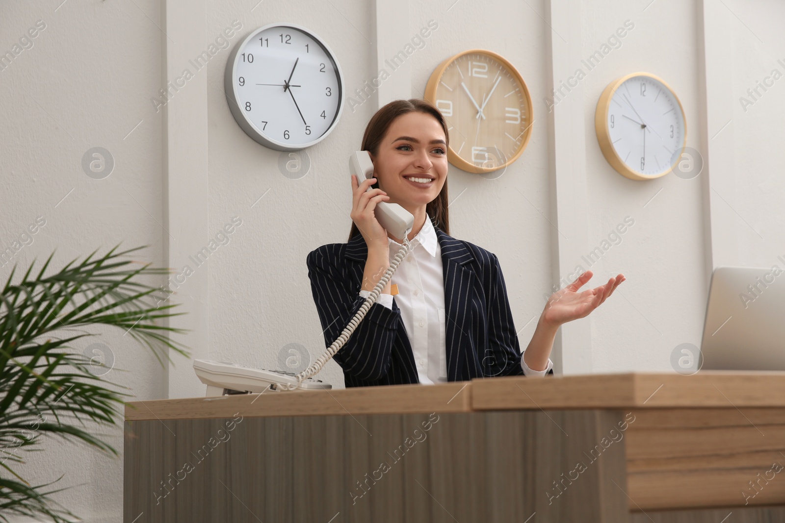 Photo of Beautiful receptionist talking on phone at counter in hotel