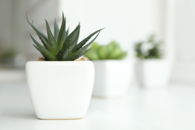 Photo of Beautiful artificial plant in flower pot on white table. Space for text