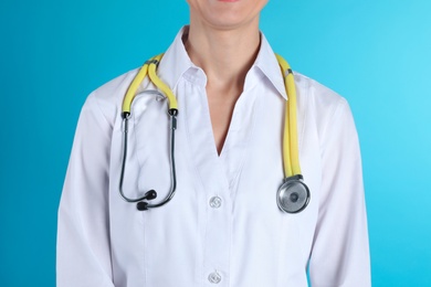 Photo of Female doctor with stethoscope on color background, closeup. Medical object