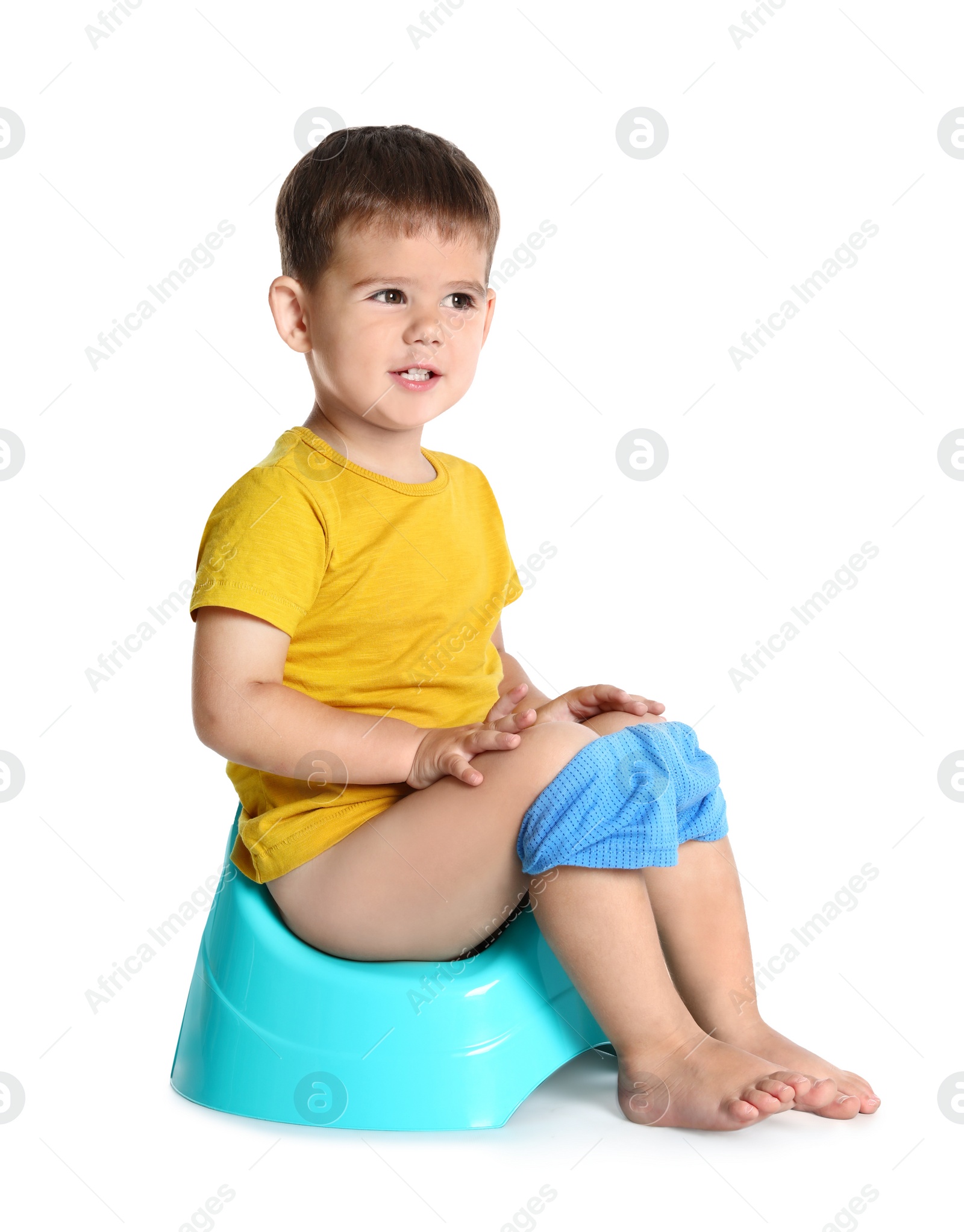 Photo of Portrait of little boy sitting on potty against white background