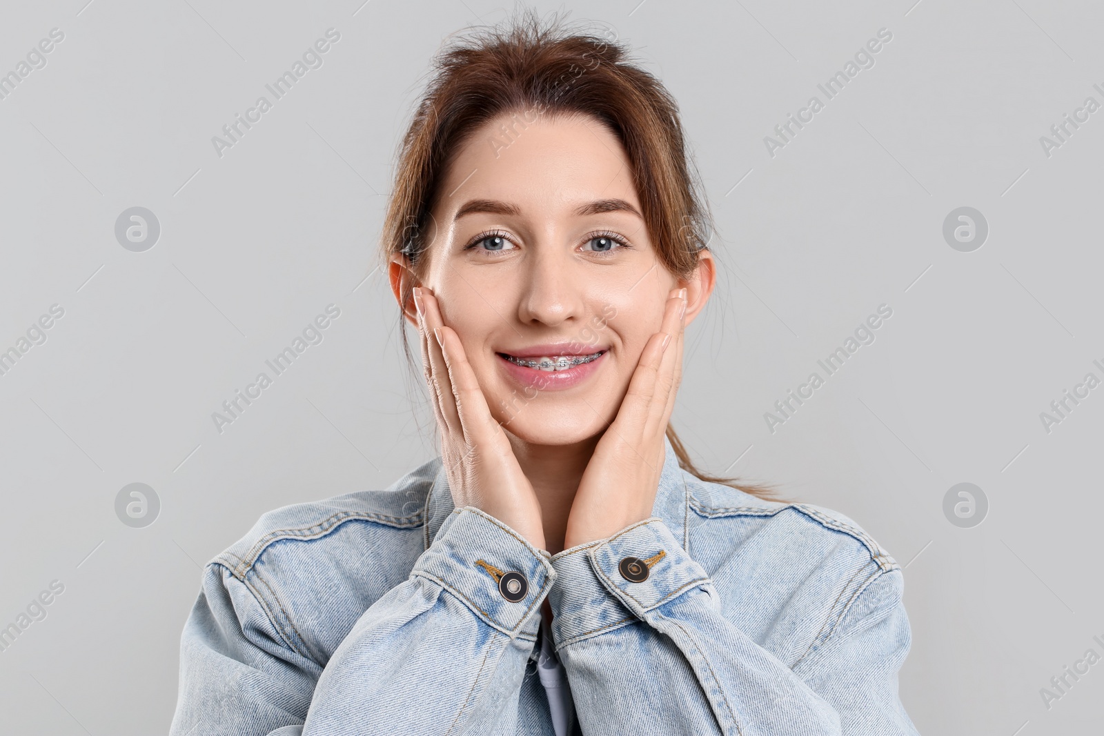 Photo of Portrait of smiling woman with dental braces on grey background