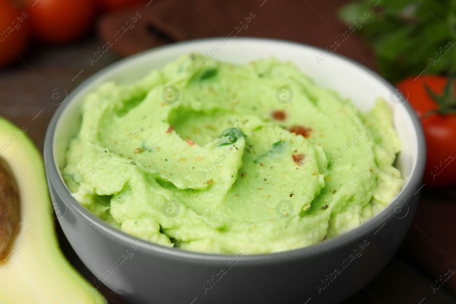 Photo of Bowl of delicious guacamole on table, closeup