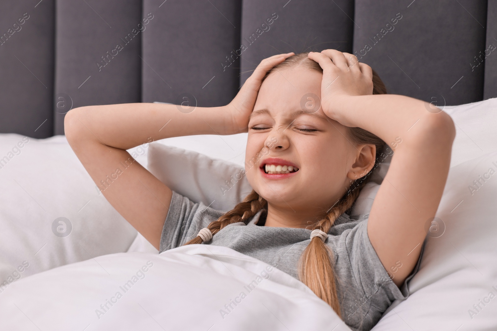 Photo of Little girl suffering from headache in bed