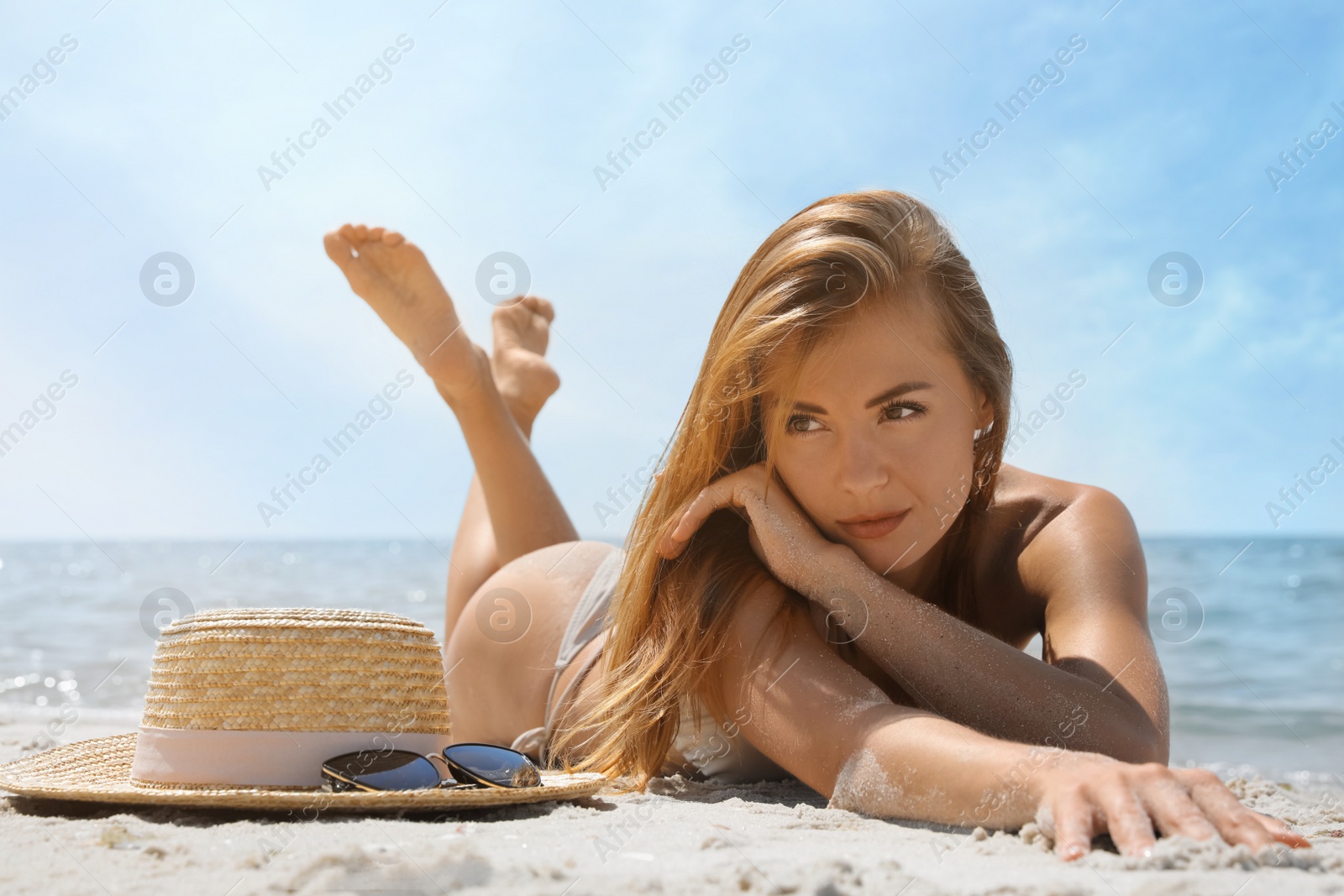 Photo of Attractive woman in bikini lying on sandy beach near sea