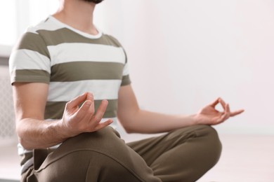 Photo of Closeup view of man meditating indoors, space for text