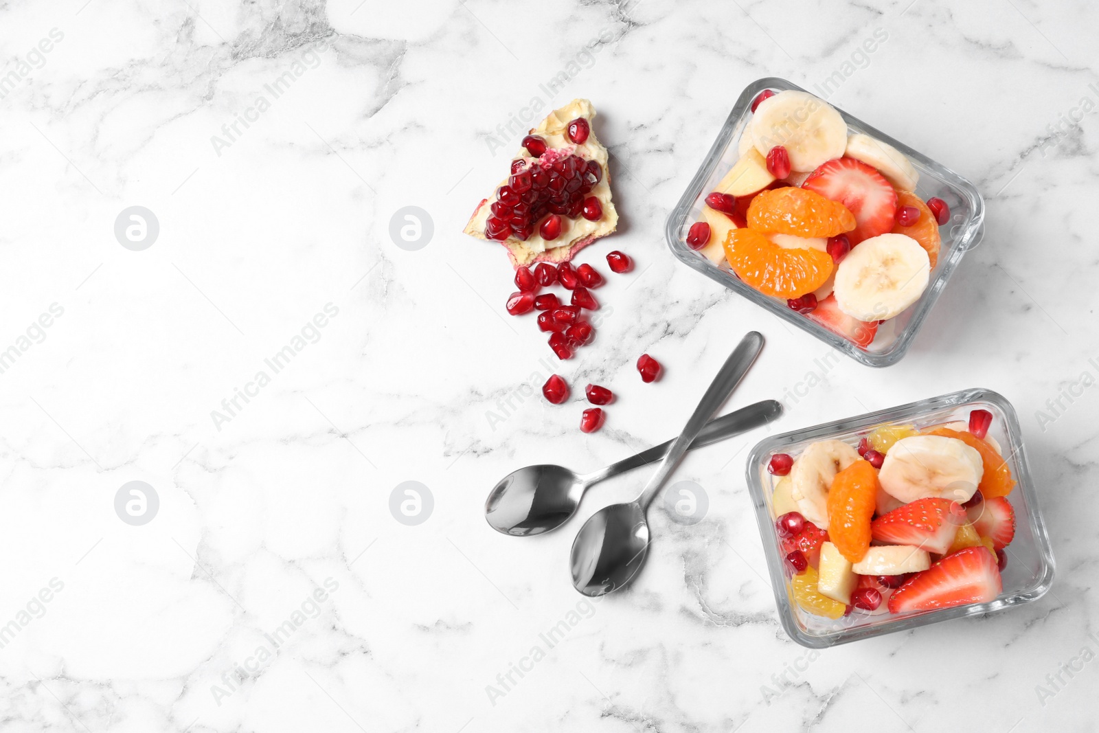 Photo of Delicious fresh fruit salad in bowls on white marble table, flat lay. Space for text
