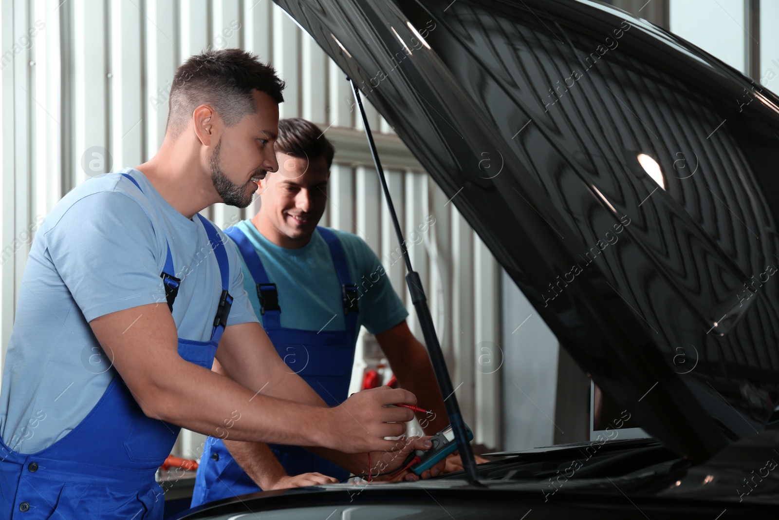 Photo of Mechanics with laptop doing car diagnostic at automobile repair shop